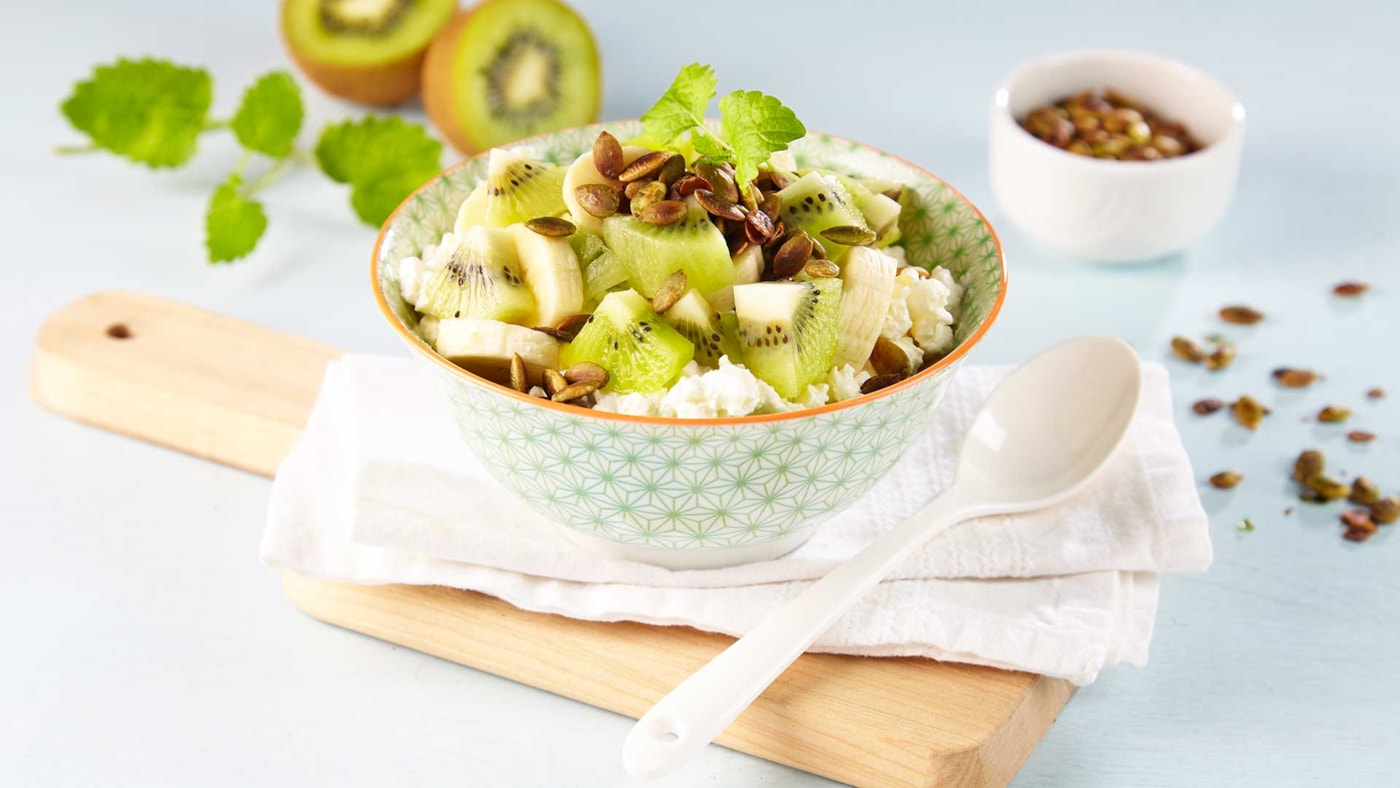 Frokostskål med cottage cheese, poppede gresskarkjerner, banan og kiwi