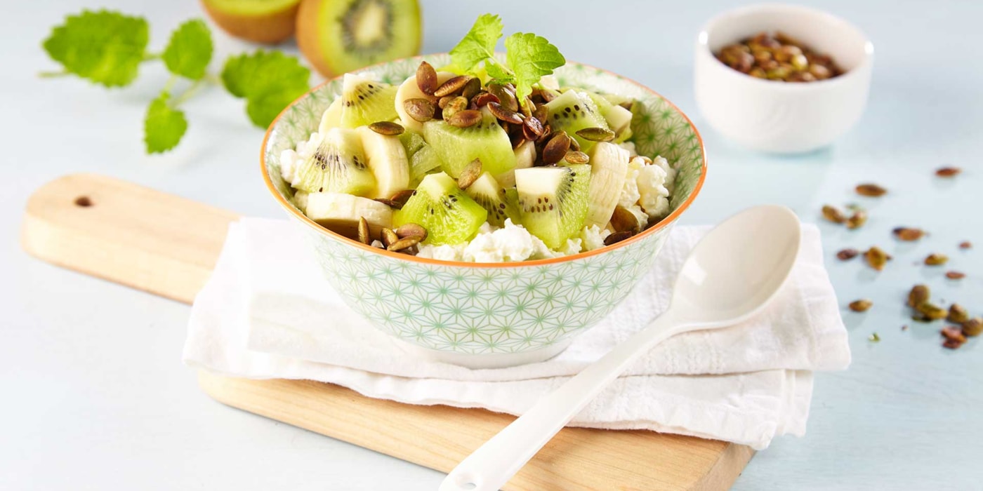 Frokostskål med cottage cheese, poppede gresskarkjerner, banan og kiwi