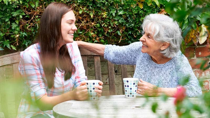 To damer drikker kaffe i hagen