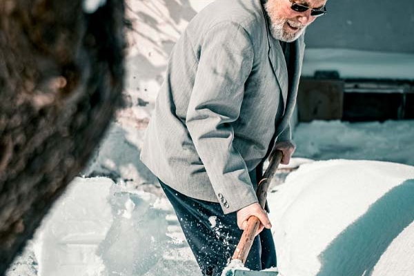 Mann som måker snø