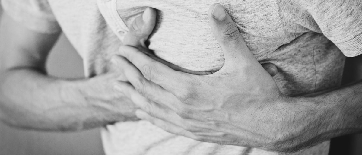 Bilde av mann som holder begge hendene inntil brystet, pga smerter