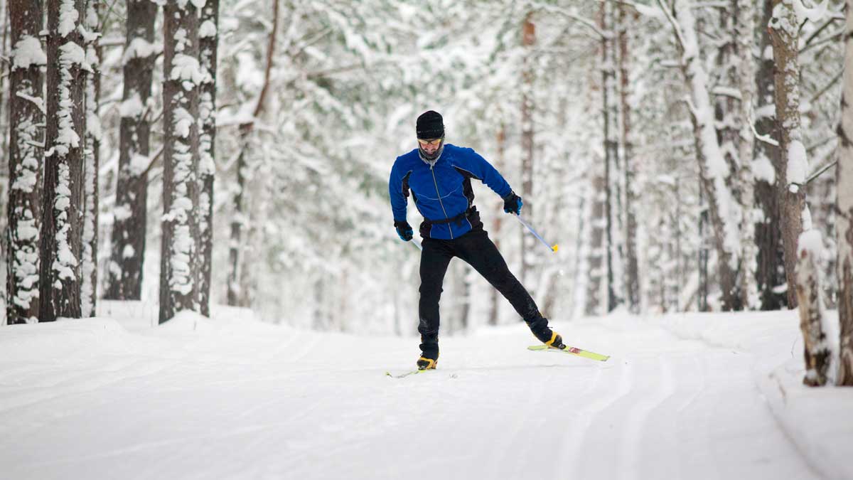 Bilde av en mann som går på langrenn i skogen er vinterdag.