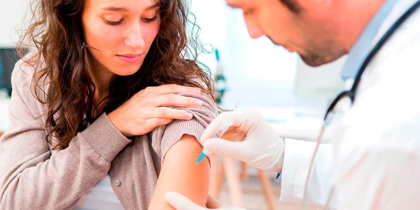 Kvinne får vaksine av lege