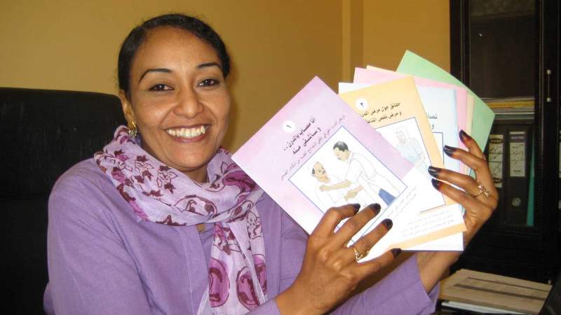 Bilde av en dame i Sudan som viser frem en rekke brosjyrer. 