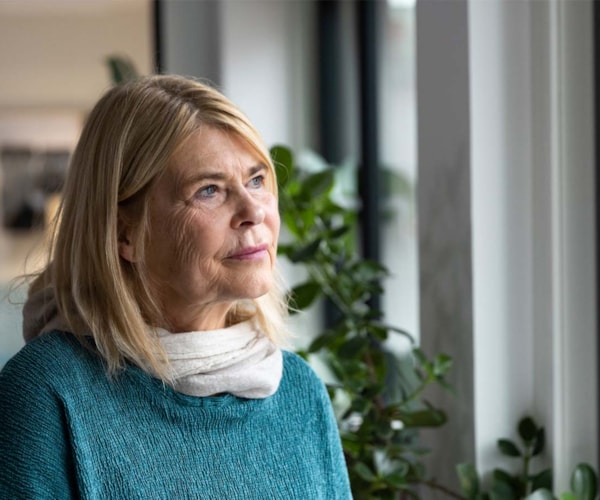 Tankefull dame ser ut av vinduet