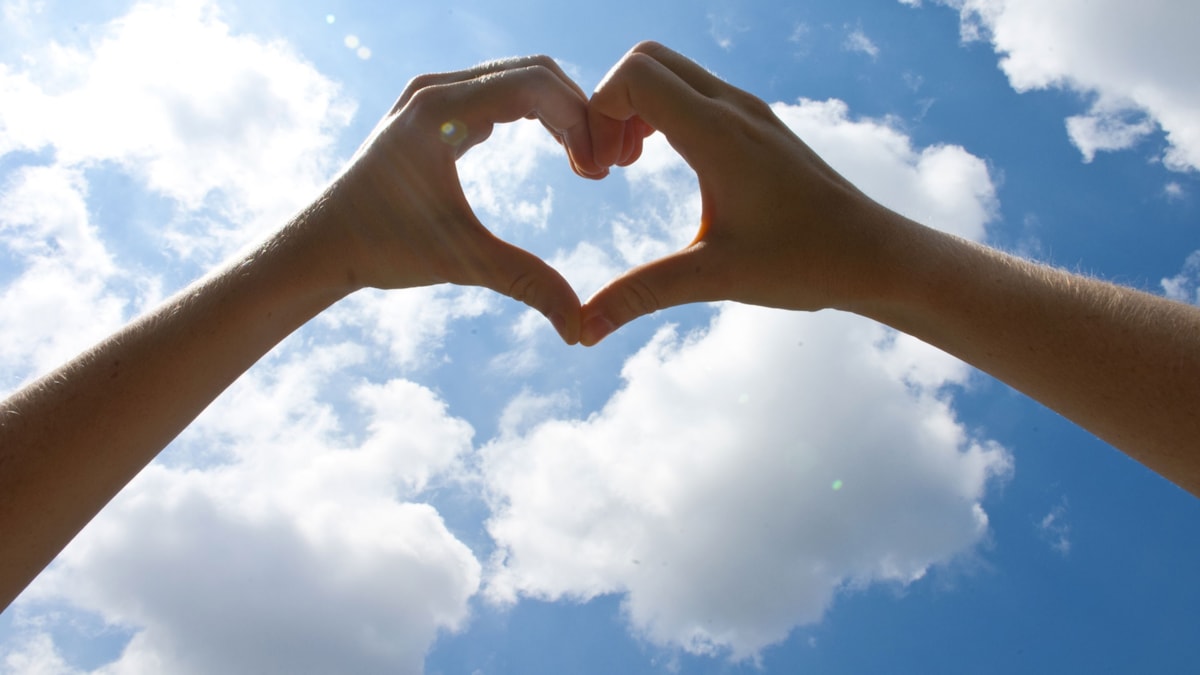 Hender som former et hjerte, mot himmelen